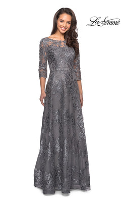 A woman wears a platinum Long Formal Dress: La Femme 27885, a long, gray sequin-lace formal dress with three-quarter sleeves and floral embroidery.