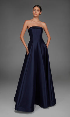 A woman wearing the Alyce 27887 long formal dress—an A-line, strapless, floor-length gown in dark navy with pockets—stands against a plain grey background.