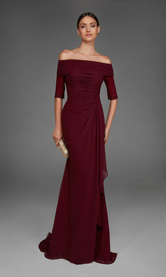 A woman poses against a plain gray background, holding a gold clutch and wearing the Long Formal Dress: Alyce 27888—a floor-length burgundy gown that showcases an elegant off-the-shoulder neckline with short sleeves.