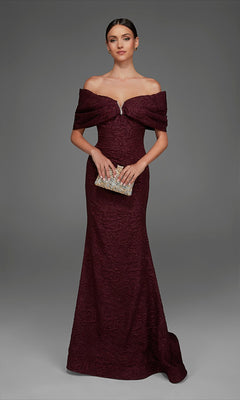 A woman wearing the Alyce 27894 long formal dress—an off-the-shoulder, dark red gown featuring textured fabric and a subtle rose-patterned brocade—holds a jeweled clutch while standing against a plain gray background.