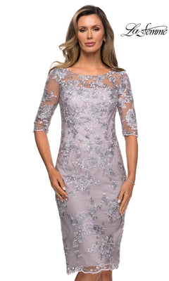 Woman models the Knee Length Wedding Guest Dress: La Femme 27895, featuring floral embroidery, sheer half sleeves, and a chic sheath silhouette. “La Femme” logo on top right.