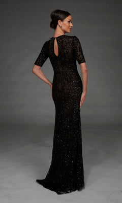 A woman stands with her back to the camera, wearing the Alyce 27901 long formal dress—a floor-length black gown with intricate lace and sequin detailing, short sleeves, and a fitted column silhouette—set against a plain dark background.