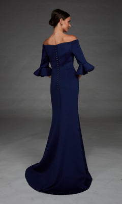 A woman is standing against a gray background, wearing the Alyce 27905—a navy blue, off-the-shoulder long formal dress with ruffled sleeves, a button-up back, and an elegant mermaid skirt.