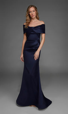 A woman stands against a plain gray background wearing the Alyce 27908, a floor-length off-the-shoulder formal gown in navy blue stretch mikado.