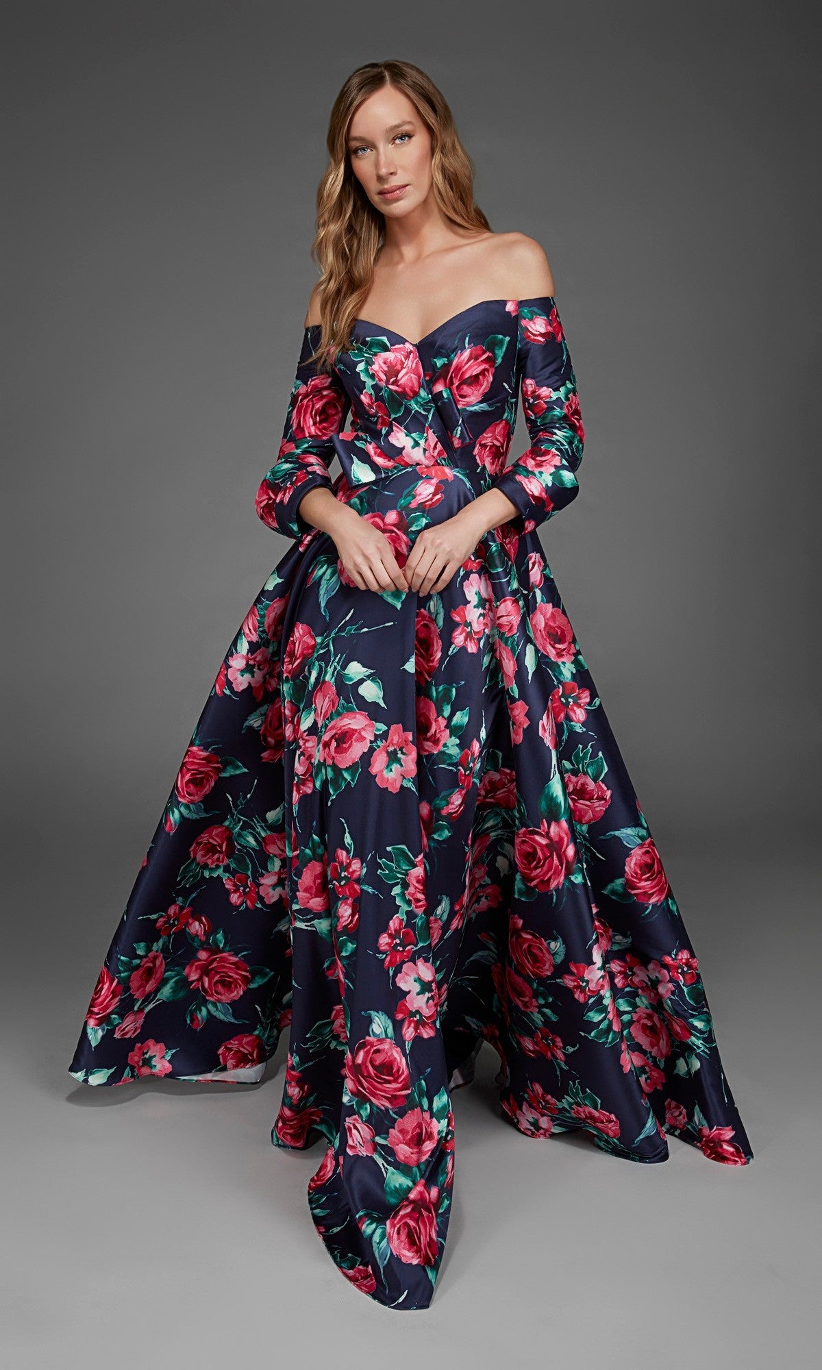 A woman wearing the Alyce 27910 long formal dress in midnight—an elegant, off-the-shoulder evening gown—stands against a plain gray backdrop.