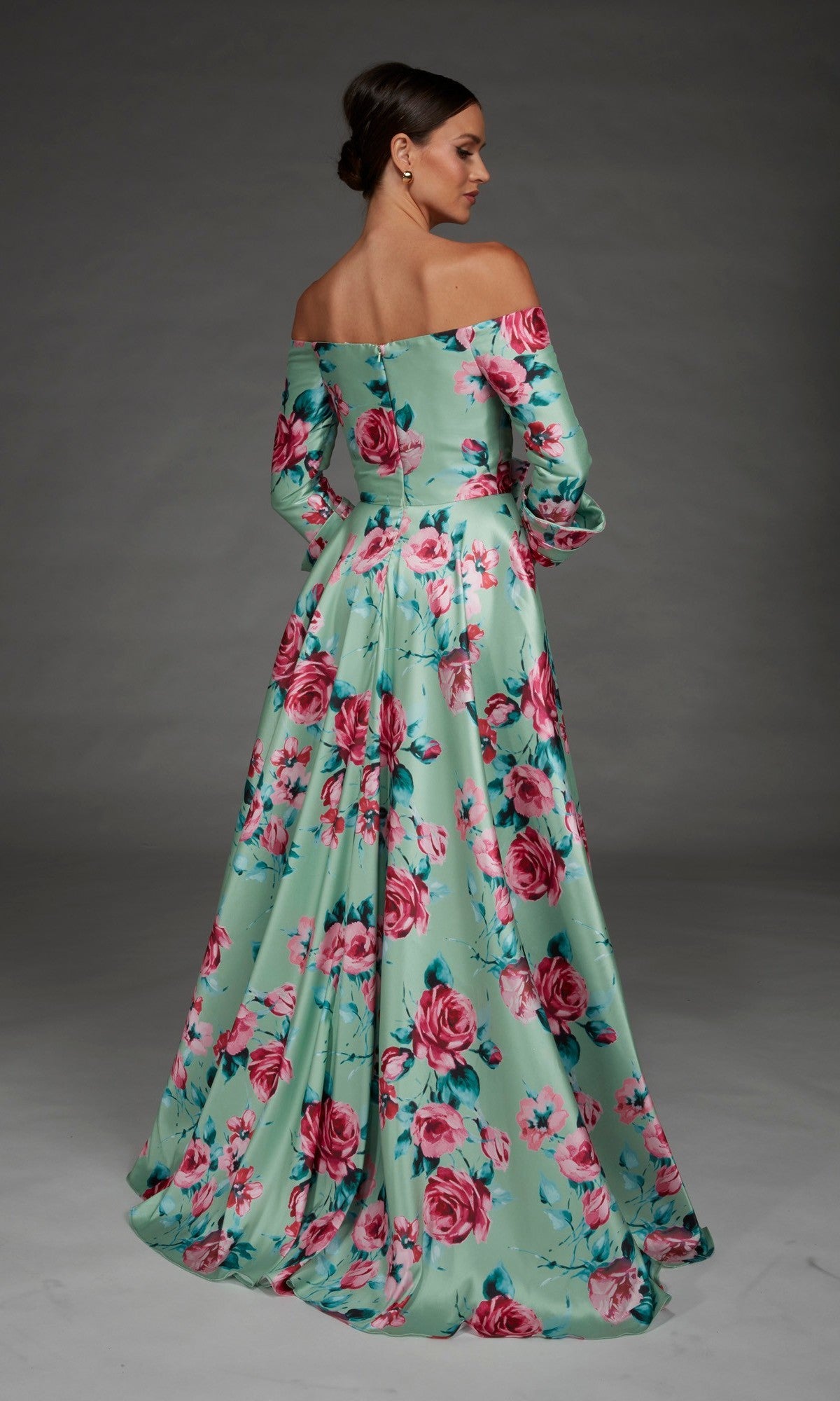 Wearing the Long Formal Dress: Alyce 27910—a floor-length, off-the-shoulder mint green gown adorned with a pink and red floral pattern—a woman stands facing away against a neutral background.