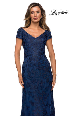 Woman wearing the Long Formal Dress: La Femme 27915, a navy blue, short-sleeved V-neck lace evening gown with floral embroidery, against a white background.