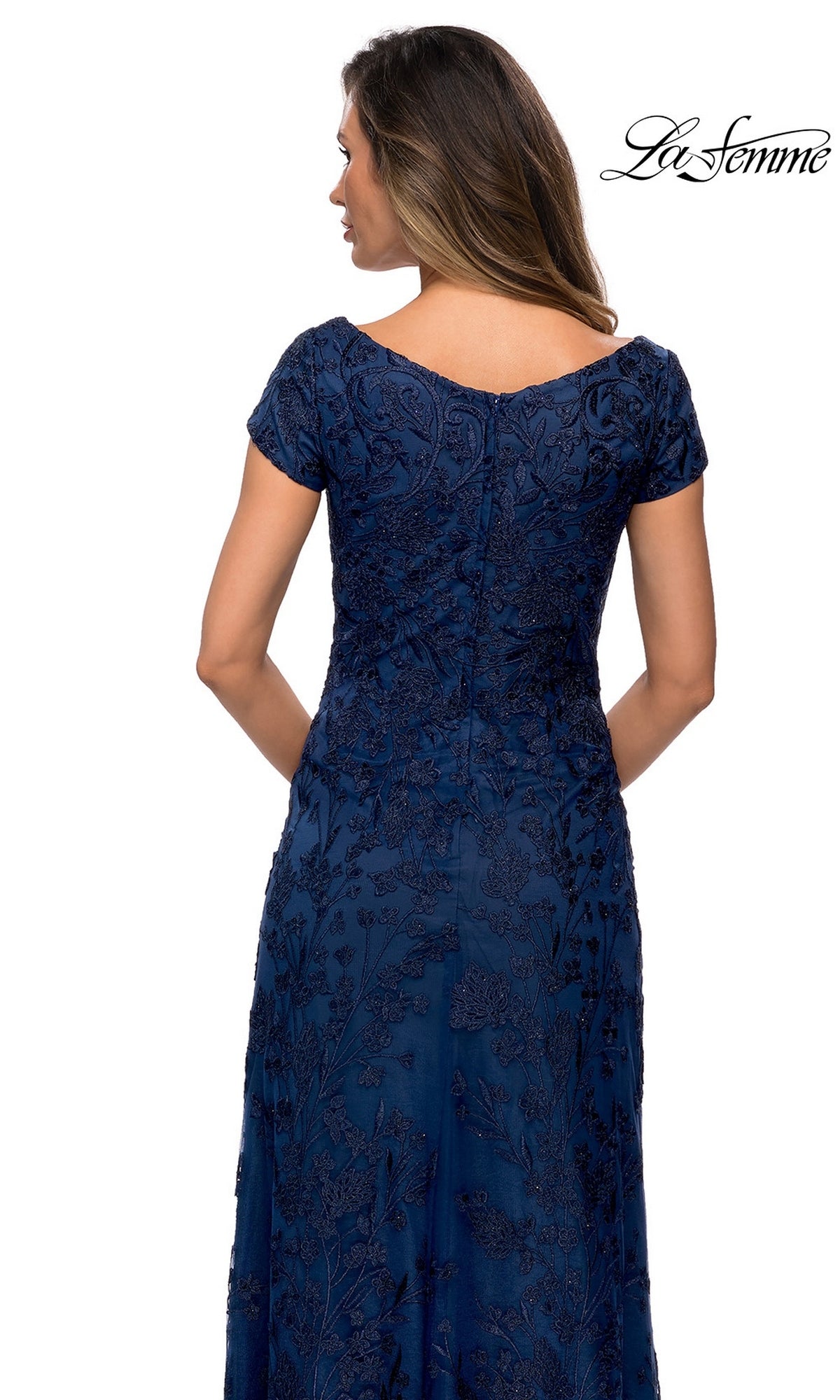 Woman in a navy blue Long Formal Dress: La Femme 27915 with floor-length lace and floral embroidery, posing with her back to the camera.