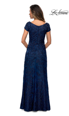 A woman facing away wears the Long Formal Dress: La Femme 27915, a floor-length, short-sleeve navy blue gown with floral patterns. “La Femme” logo at top right on white background.