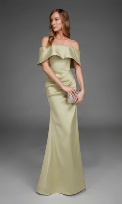 Wearing the Alyce 27916 Long Formal Dress in honeydew, a woman elegantly holds a silver clutch as she stands gracefully against a plain gray background.