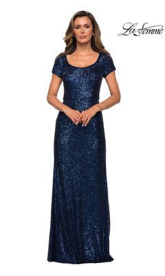 A woman wears a floor-length, navy blue sequin La Femme 27916 formal dress with short sleeves and a scoop neckline.