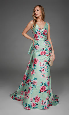 A woman poses against a plain gray background wearing the Alyce 27917 long formal dress—a sleeveless, mint green v-neck evening gown with a pink floral print—while holding a beige clutch.