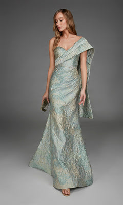 A woman wearing the Alyce 27918 long formal dress—a shimmering, metallic jacquard one-shoulder gown with a side drape—holds a clutch and stands against a plain gray background.