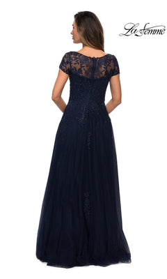 Woman in a floor-length, navy blue “Long Formal Dress: La Femme 27920” with floral lace short sleeves and sheer lace back, facing away; “La Femme” logo at top right.
