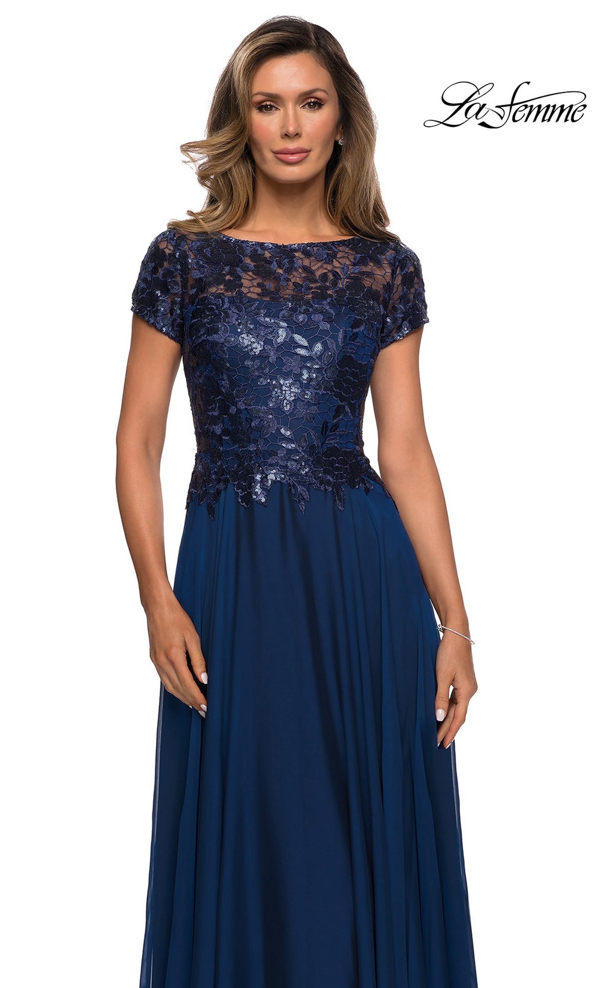 Woman wearing Long Formal Dress: La Femme 27924, with a metallic lace bodice, short sleeves, and a flowing navy blue skirt.