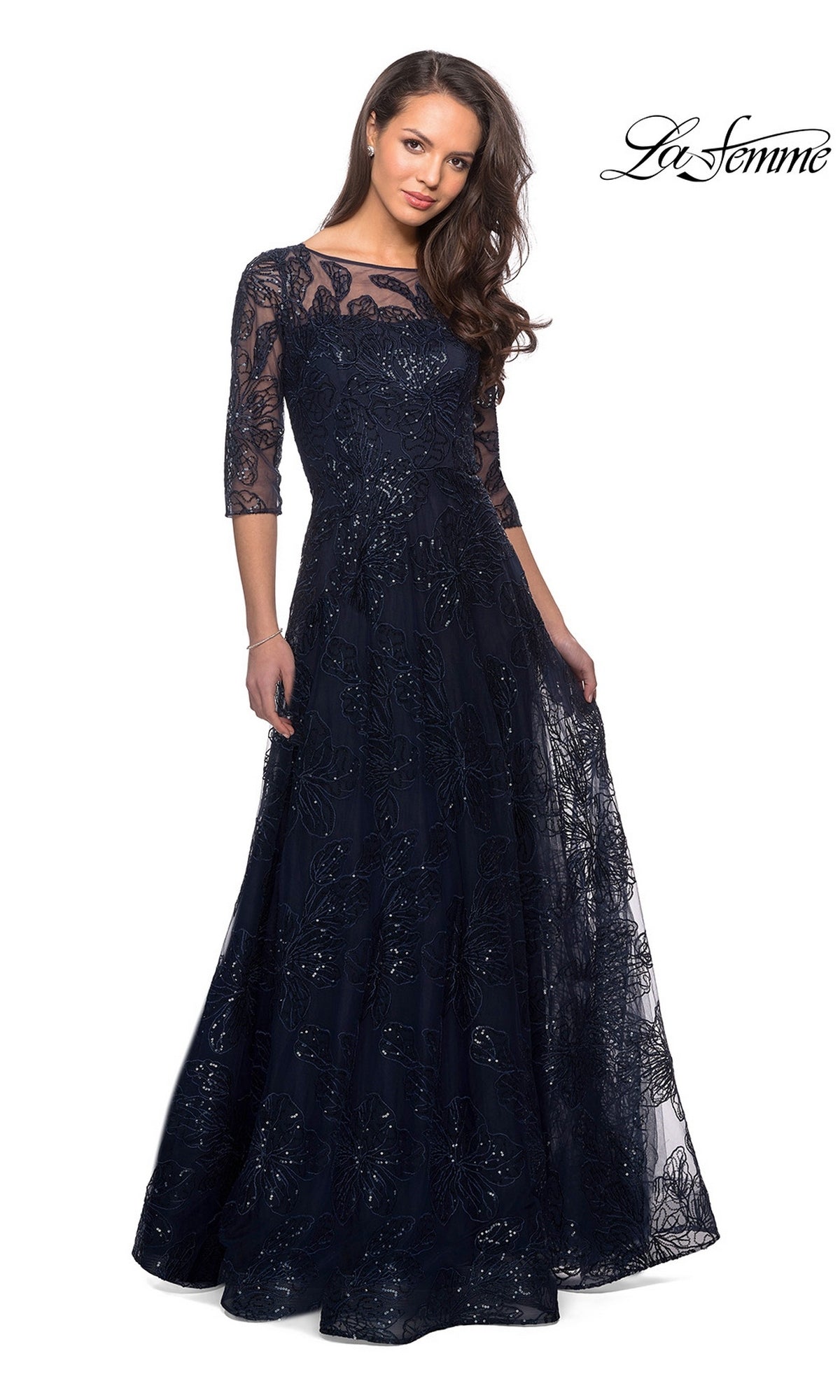 A woman wears the Long Formal Dress: La Femme 27942 in navy, a floor-length sequined lace gown with three-quarter sleeves, against a white background.