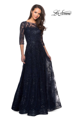 A woman wears the Long Formal Dress: La Femme 27942 in navy, a floor-length sequined lace gown with three-quarter sleeves, against a white background.