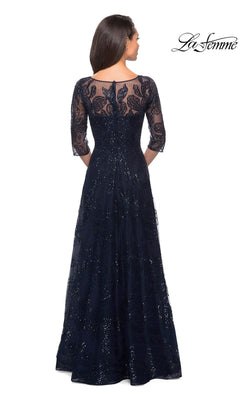 A woman faces away in the Long Formal Dress: La Femme 27942, a floor-length sequined lace gown with three-quarter sleeves, sheer back, and elegant floral patterns.