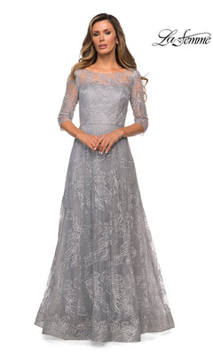 A woman stands facing forward in the Long Formal Dress: La Femme 27942, a silver, modest, floor-length gown with three-quarter sleeves and floral lace details. La Femme logo top right.