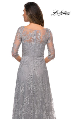 Woman in a sheer, embroidered gray Long Formal Dress: La Femme 27942 with three-quarter sleeves is shown from the back, head turned slightly. “La Femme” logo appears above.