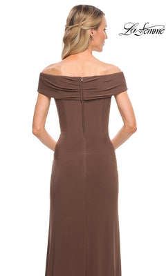 A blonde woman with loose waves models the Long Formal Dress: La Femme 27959—an off-shoulder, brown, floor-length jersey gown—photographed from the back on a white backdrop.