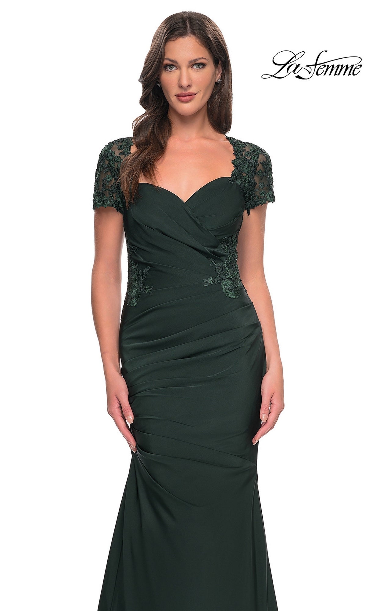 A woman poses against a white background wearing the La Femme 27989 long formal dress—crafted from dark green satin-jersey with lace short sleeves and ruched detailing, and featuring a floor-length silhouette.