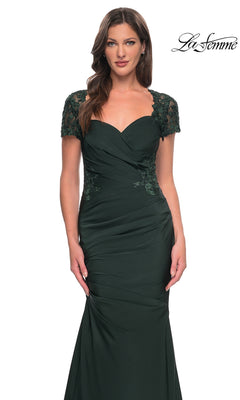 A woman poses against a white background wearing the La Femme 27989 long formal dress—crafted from dark green satin-jersey with lace short sleeves and ruched detailing, and featuring a floor-length silhouette.