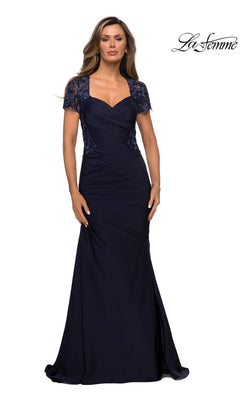 A woman stands against a white background wearing the La Femme 27989 long formal dress in navy, a floor-length evening gown with lace short sleeves, a ruched bodice, and delicate lace appliqué.