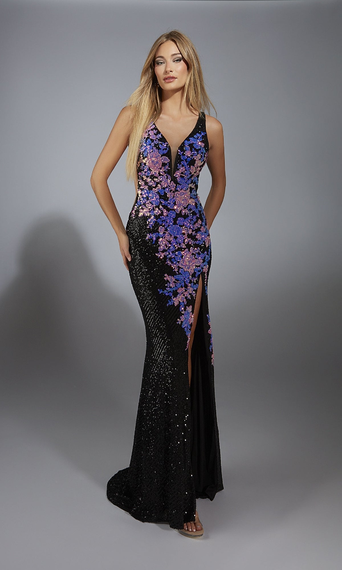 A woman models the Aerie Couture 279 Long Formal Dress—a black gown with a deep V-neck, lace-up back, purple and pink floral embellishments, and a thigh-high slit—standing against a neutral background.