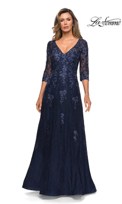 Woman wearing Long Formal Dress: La Femme 28000 in navy, with floral lace, V-neckline, and three-quarter sleeves. “La Femme” logo in the top right corner.