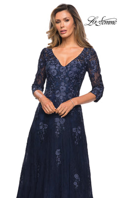 Woman wearing the Long Formal Dress: La Femme 28000 in navy with floral lace, three-quarter sleeves, and a V-neckline, posing against a white background.