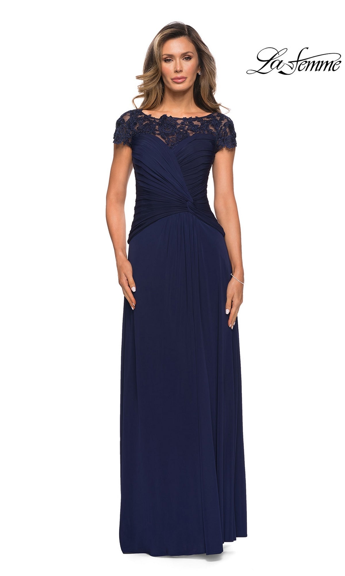 Woman in La Femme 28029, a floor-length navy blue modest dress with lace cap sleeves and ruched detailing, stands against a white background with the “La Femme” logo.