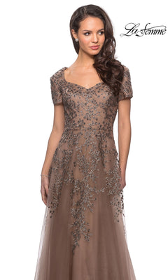 A woman wears a taupe La Femme 28037 long formal dress with an embellished sweetheart neckline, intricate floral embroidery, and an A-line tulle skirt.