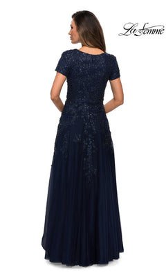 A woman wearing the Long Formal Dress: La Femme 28037, seen from behind in a navy blue, floor-length A-line tulle gown with beaded appliques on the lace and sequin bodice and hips.