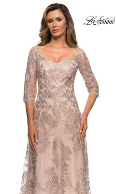 A woman wears the Long Formal Dress: La Femme 28053, a light pink, floor-length gown with floral embroidery and sheer sleeves, against a white background. “La Femme” logo top right.
