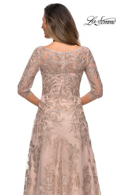 Woman in Long Formal Dress: La Femme 28053, light blush with silver floral embroidery, three-quarter sleeves, sheer details, facing away from the camera.