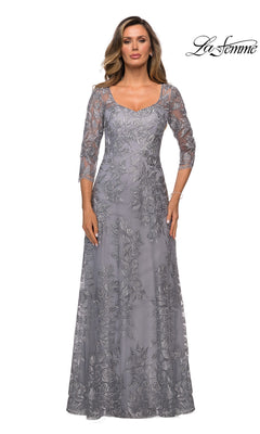 Woman in a long silver Long Formal Dress: La Femme 28053 with sheer floral lace overlay and three-quarter sleeves, standing against a white background.