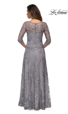 Woman wearing Long Formal Dress: La Femme 28053, a silver, embroidered gown with long sleeves and floor-length skirt, standing with her back to the camera. “La Femme” logo at top right.