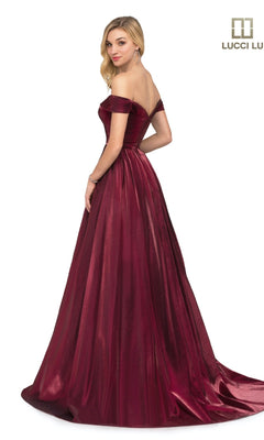 A woman stands, looking over her shoulder in the Lucci Lu 28063 off-the-shoulder, floor-length satin prom dress with a flared skirt. The Lucci Lu logo appears in the top right corner.