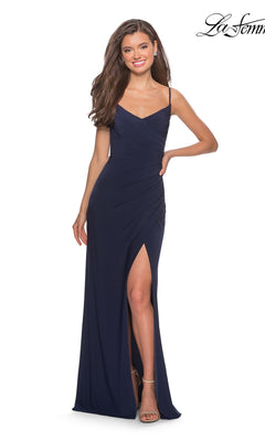 Smiling with one hand on her hip, the woman is wearing the La Femme 28079 Long Prom Dress in Navy—a sleeveless evening gown featuring a flattering faux wrap design, a sweetheart neckline, and a thigh-high leg slit.