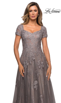 A woman wears a mauve, floor-length La Femme 28091 formal dress with a sweetheart neckline, short sleeves, and floral lace appliques.