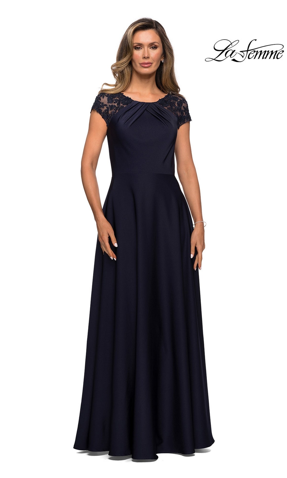 A woman stands against a white background wearing the Long Formal Dress: La Femme 28100 in navy, a floor-length gown featuring short sleeves, lace shoulder detailing, and an elegant A-line silhouette. The words “La Femme” appear in the top right corner.