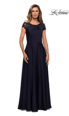 A woman stands against a white background wearing the Long Formal Dress: La Femme 28100 in navy, a floor-length gown featuring short sleeves, lace shoulder detailing, and an elegant A-line silhouette. The words “La Femme” appear in the top right corner.