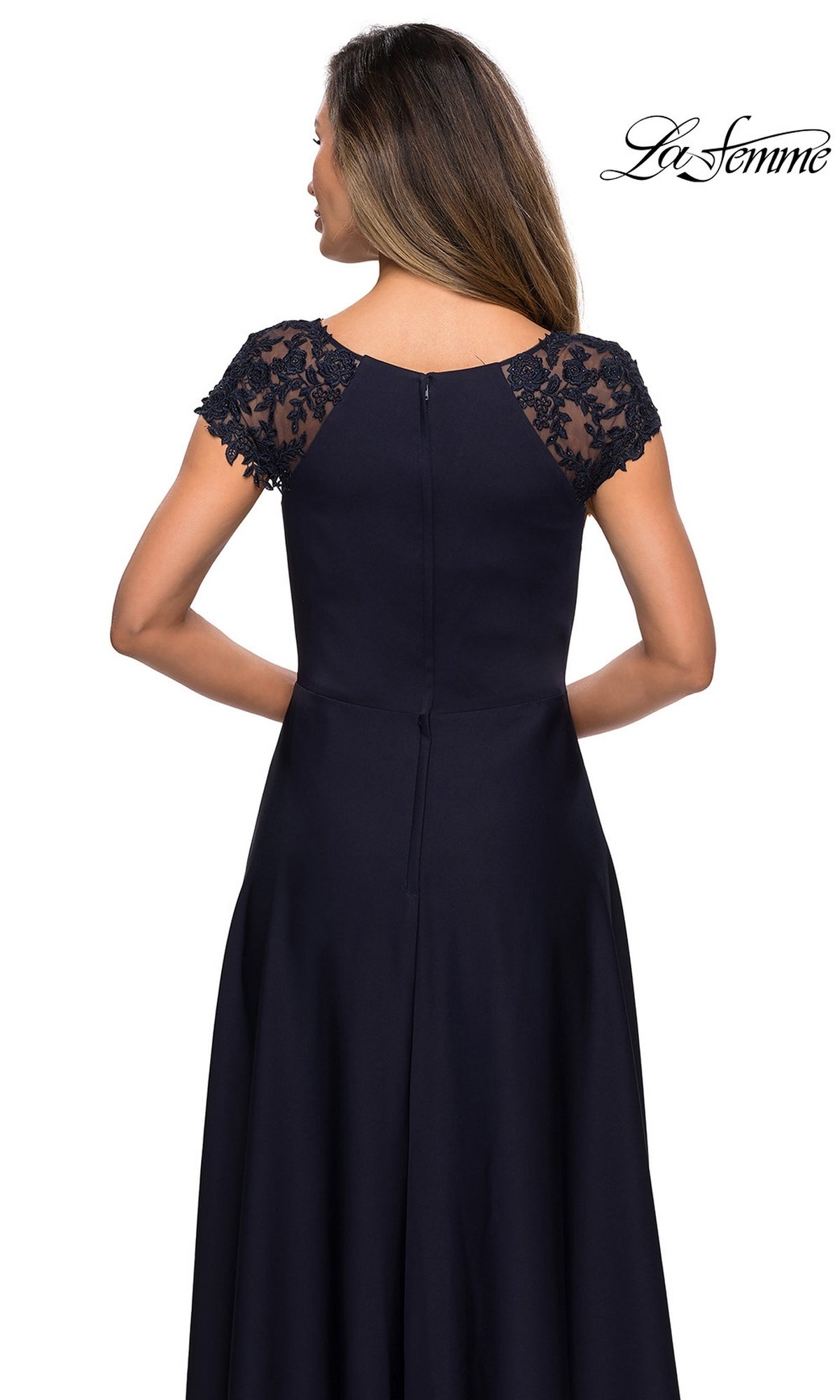 A woman is shown from the back wearing the Long Formal Dress: La Femme 28100 in navy blue, featuring short lace sleeves, a fitted bodice, an A-line silhouette, and a flowing skirt. The “La Femme” logo appears in the upper right corner.