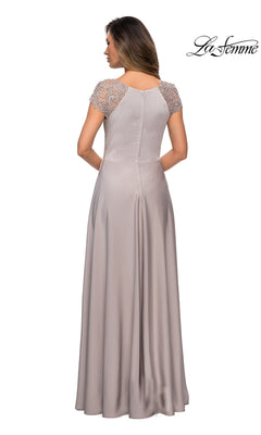 A woman is seen from the back wearing the Long Formal Dress: La Femme 28100, a floor-length light lavender gown with short lace-detailed sleeves and an elegant A-line silhouette.