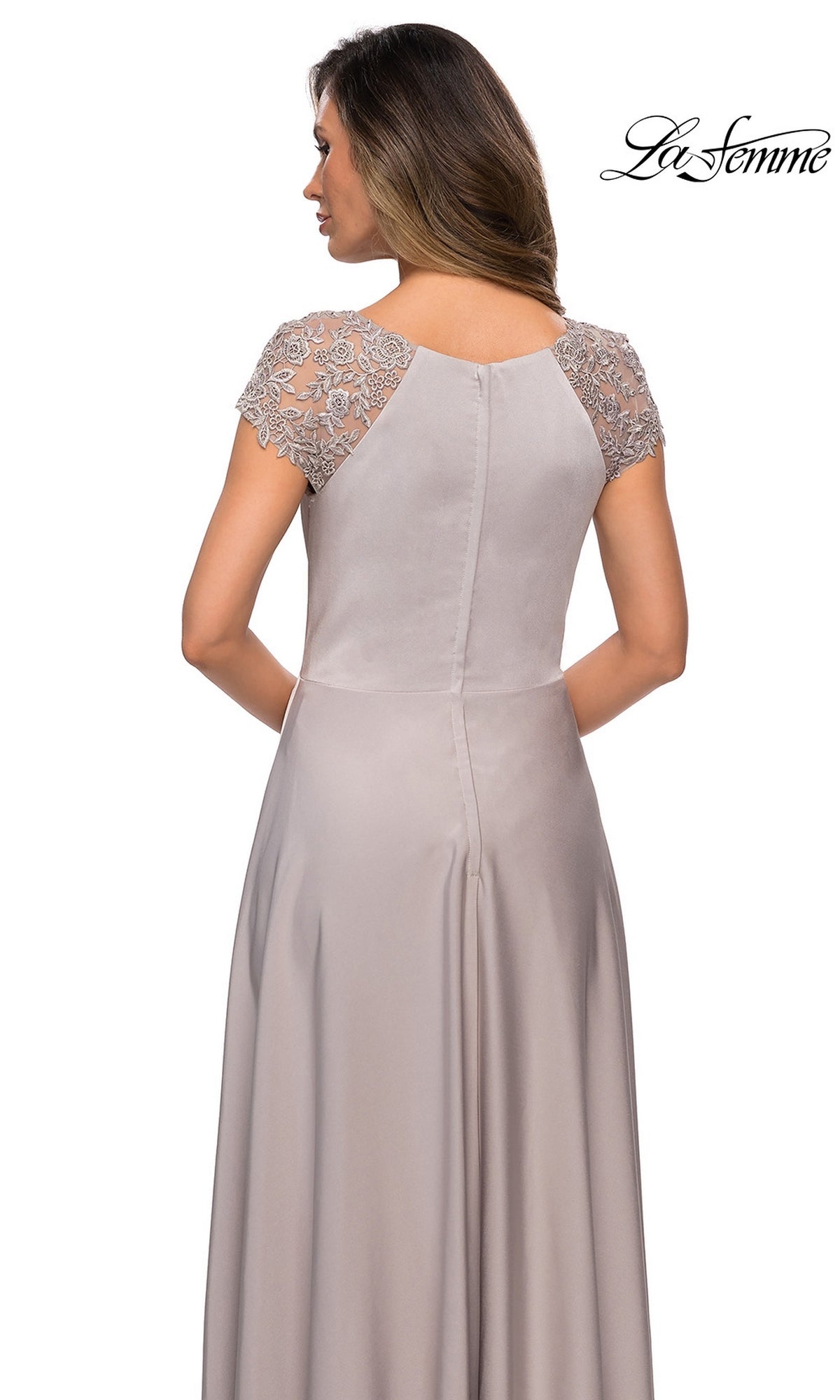 A woman is seen from behind wearing the Long Formal Dress: La Femme 28100—a floor-length taupe gown with short, sheer embroidered sleeves and a zipper back. Showcasing an elegant A-line silhouette, this modest dress exudes timeless sophistication. The “La Femme” logo is displayed in the top right corner.