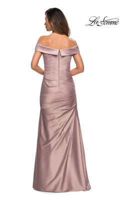 A woman stands facing away, showcasing the back zipper and ruched detailing of the La Femme 28103 long formal dress. This elegant mauve, floor-length gown features a satin finish and an off-the-shoulder neckline—perfect for a sophisticated mother-of-the-bride look. “La Femme” logo appears in the top right corner.