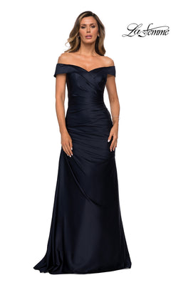 A woman wears the La Femme 28103 long formal dress in navy, featuring an off-the-shoulder neckline, floor-length fitted silhouette, and subtle pleating, standing against a white background. Ideal as a satin mother-of-the-bride gown. The “La Femme” logo appears in the top right corner.