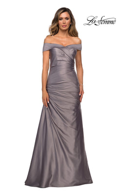 A woman wears the La Femme 28103, a platinum, off-the-shoulder, floor-length satin formal dress featuring ruched detailing; the “La Femme” logo appears in the top right corner—perfect for an elegant mother-of-the-bride look.