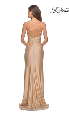 A woman models the La Femme Open-Back Long V-Neck Prom Dress 28206 in gold satin, featuring thin crisscross straps, an open back, and waist ruching, as she stands against a white background.